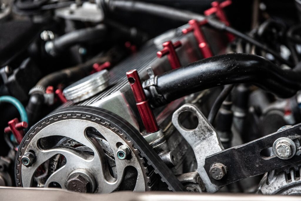 Closeup of black thick hosepipes and timing belt on metallic detail of car engine in daylight